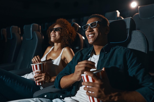 Couple watching comedy in 3d glasses with popcorn