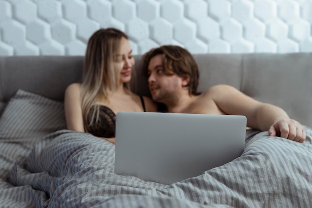 Photo couple watching porn movie over laptop in bedroom