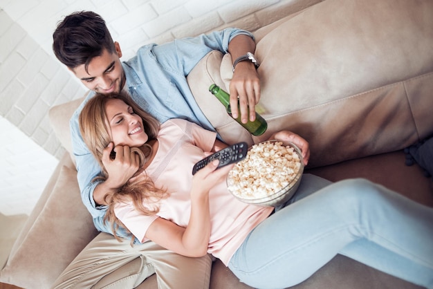 Пара смотрит телевизор и ест попкорн
