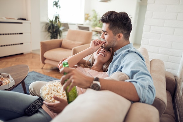 Couple watching TV and eating popcorn