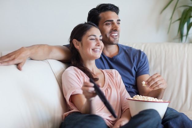 カップルがテレビを見ながらポップコーンを食べる