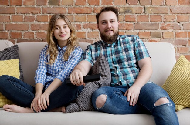 Photo couple watching tv while sitting on sofa at home