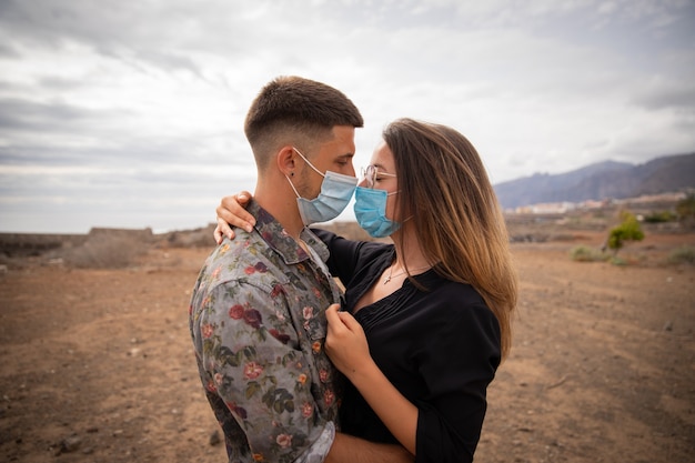 Couple wear surgical masks, during a moment of cuddles, to stay safe from the Coronavirus Pandemic in Tenerife.