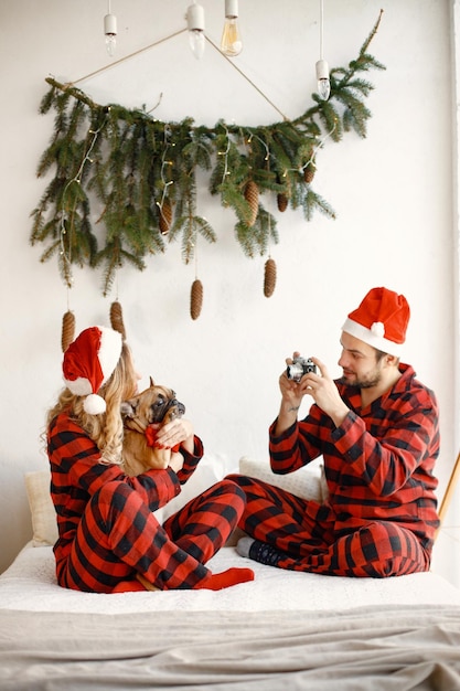 Couple wearing christmas plaid red pajamas make a photo with a dog