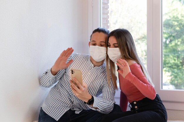Couple wearing a face mask while videocalling their family during quarantine