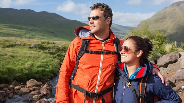 Couple wearing rain jackets and sunglasses admiring the countryside