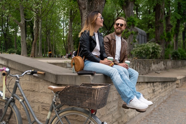 Couple wearing synthetic leather jackets having coffee together outdoors