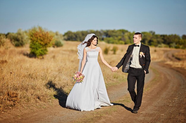 花の花束を持つ結婚式の服装のカップル