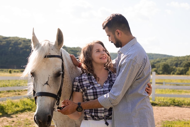 牧場でのカップルと白い馬