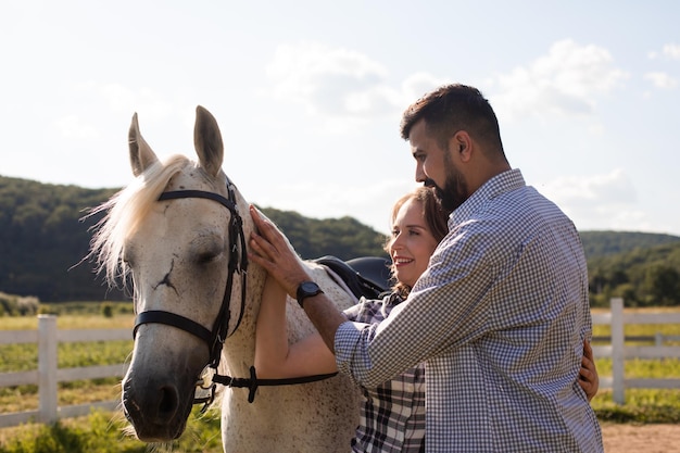 牧場でのカップルと白い馬