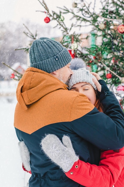 Couple winter decorated christmas tree background Enjoying spending time together in New Year Eve Two lovers are hugging and kissing in Saint Valentine's Day