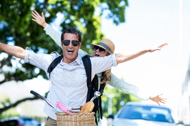 Couple with arms outstretched on bicycle