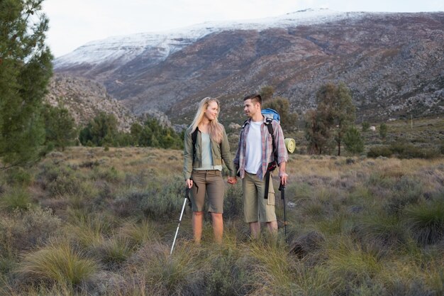 Couple with backpacks and trekking poles against mountain