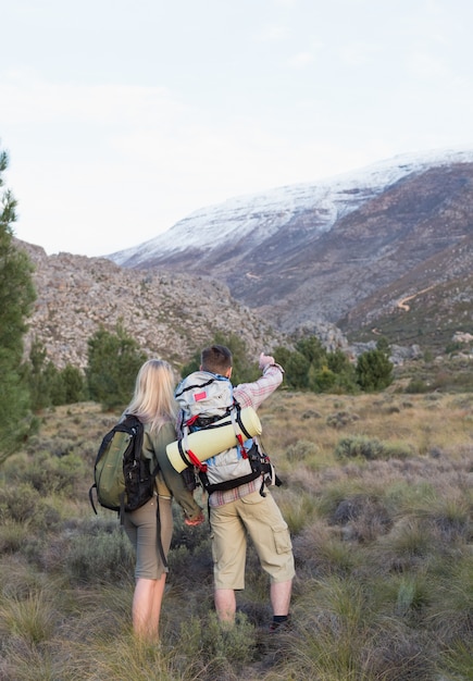 Couple with backpacks walking on forest landscape