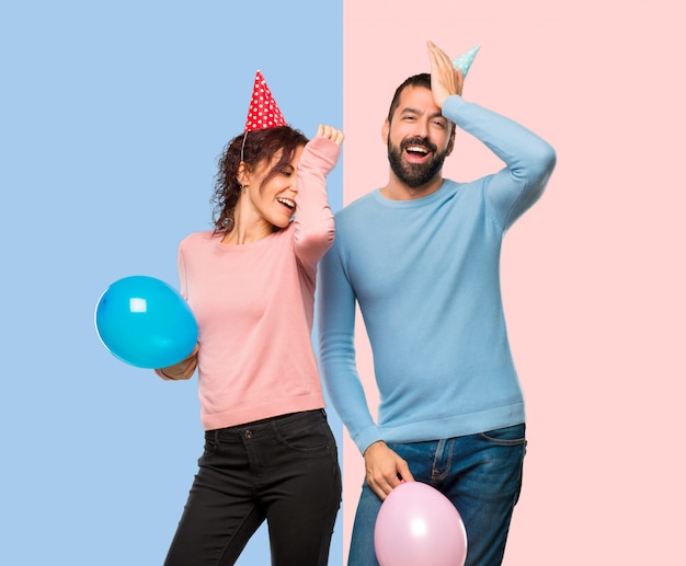 Couple with balloons and birthday hats has just realized something and has intending the s