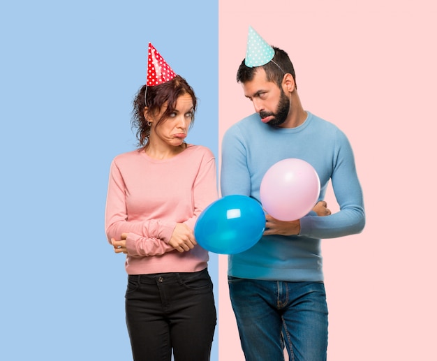 Пара с воздушными шарами и ко дню рождения с грустным и подавленным выражением.
