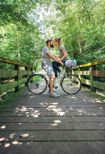 Couple with bicycle about to kiss on a wooden walkway in the countryside