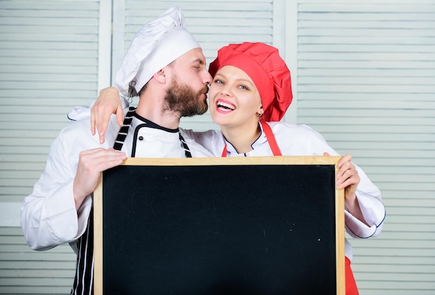 Couple with blackboard for advertisement Lovely family at kitchen Family restaurant Family day Couple in love cooking together Family values Share joy Man and woman chef cooking food together