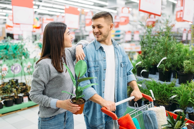 Coppia con carrello acquisto casa fiore nel supermercato