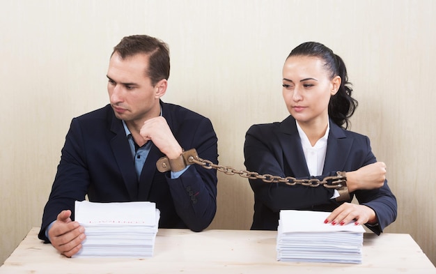 Couple with chained hands reading a contract concept