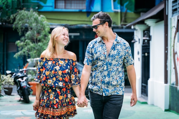 Couple with colorful floral dresses walking hand in hand on a street with colorful facades