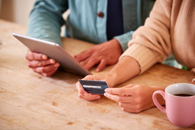 Couple With Credit Card At Home Use Digital Tablet To Review Finances For Starting Business