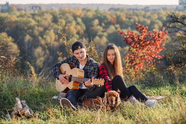 Couple with guitar and their dog having a picnic in the park