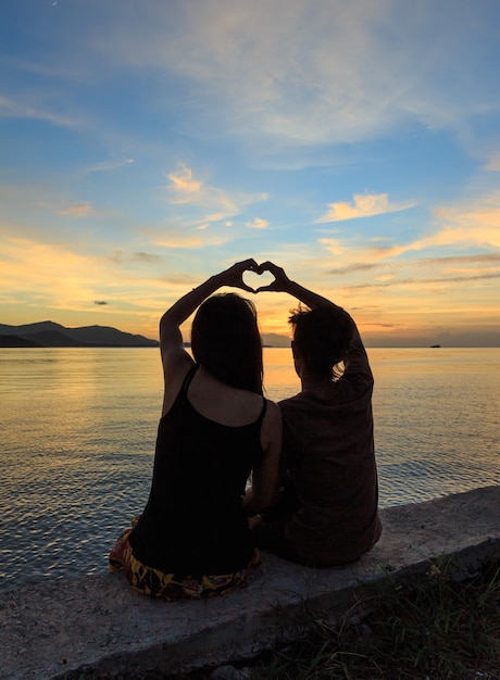 Couple with heart finger symbol at dusk