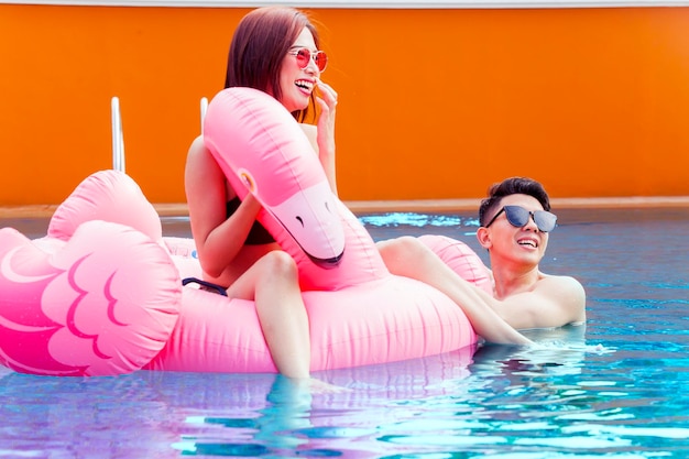 Couple with inflatable flamingo on swimming pool