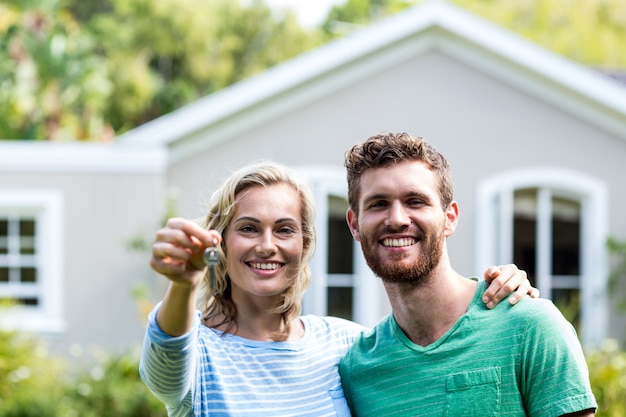 Photo couple with keys standing against house