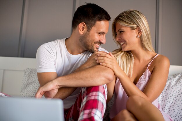 Couple with laptop in bed