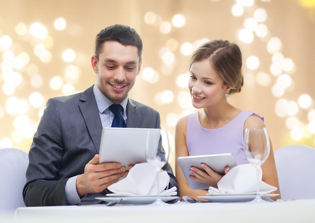 couple with menu on tablet computers at restaurant