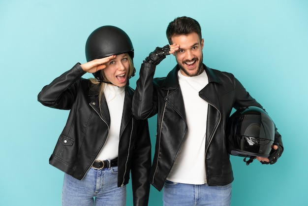 Couple with motorcycle helmet over isolated blue background has just realized something and has intending the solution