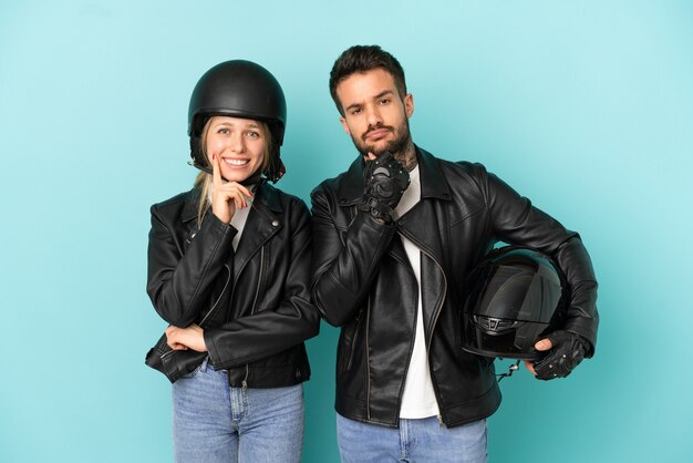 Couple with motorcycle helmet over isolated blue background smiling with a sweet expression