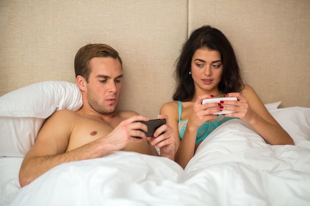 Photo couple with phones in bed.