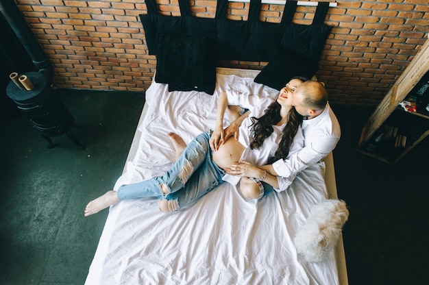 Couple With Pregnant Woman Relaxing On Sofa Together with dog