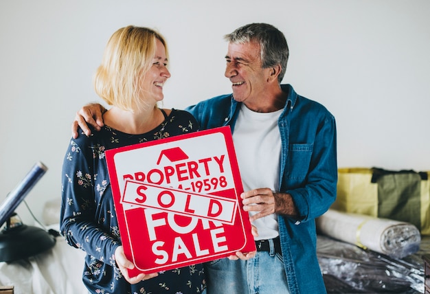 Couple with a property for sale sign