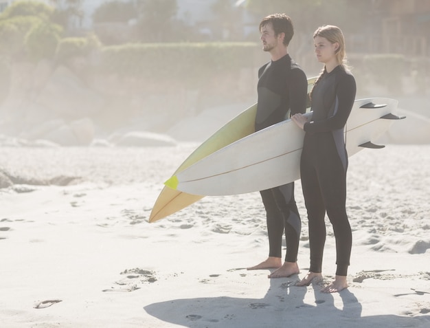 Couple with surfboard standing on the beach