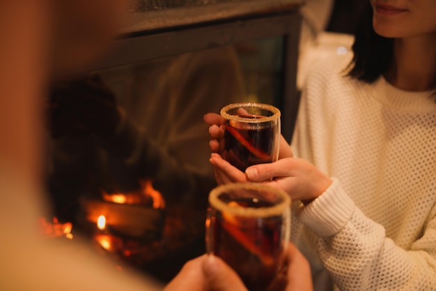 Couple with tasty mulled wine near fireplace indoors closeup