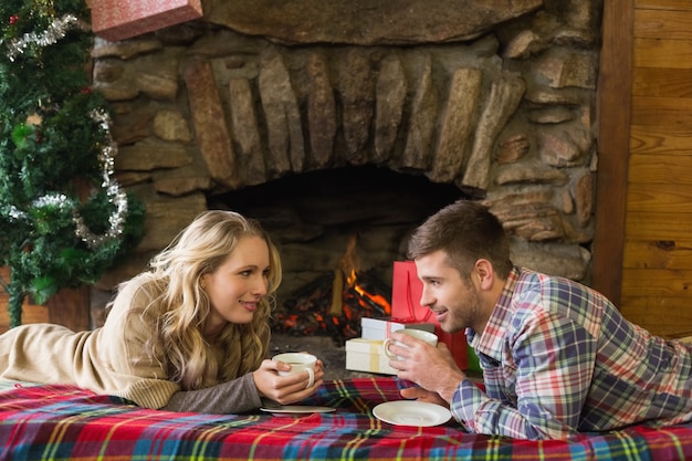 Photo couple with tea cups in front of lit fireplace