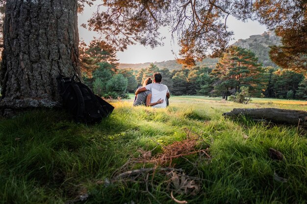 Photo couple with their backs to each other hugging in the middle of nature