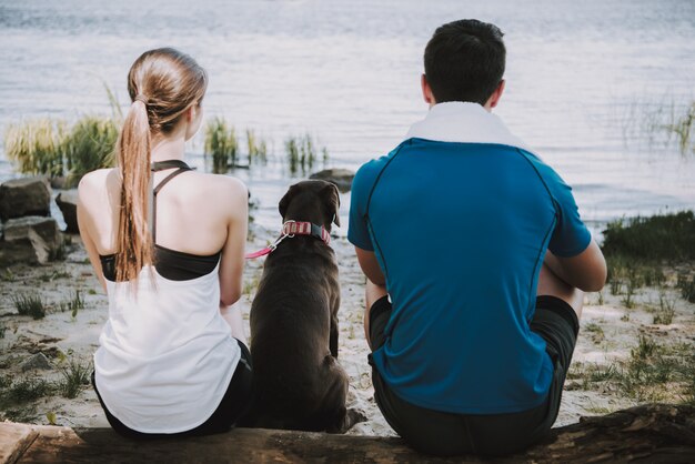 Coppia con il loro cane sulla riva del fiume nel parco verde