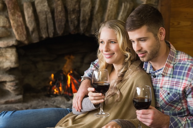 Couple with wineglasses in front of lit fireplace