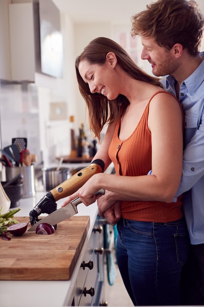 Foto coppia con la donna con il braccio protesico in cucina a preparare il pasto insieme