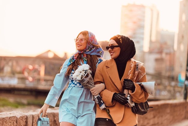 Пара женщин, одна в хиджабе и современном, но традиционном платье, а другая в синем платье