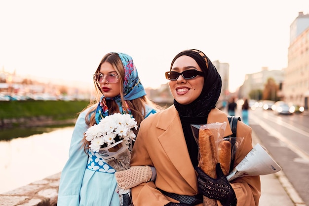 カップルの女性の 1 人はヒジャブとモダンだが伝統的なドレスを着ており、もう 1 人は青いドレスを着ており、