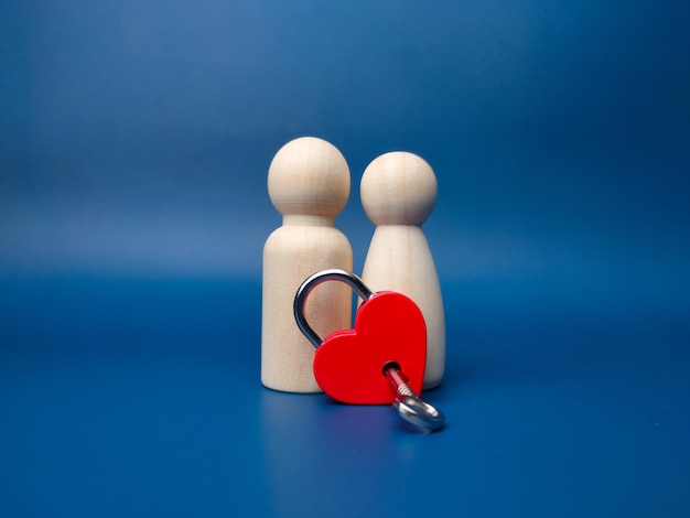 Photo couple wooden peg doll with love padlock and key on a blue background