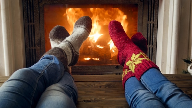 Couple in wool socks relaxing in chalet at burning fireplace