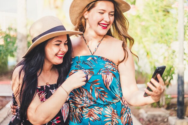 Couple of young females caucasian people friends enjoy the outdoor leisure activitry together using modern connection and smart phone to communicate and have fun together