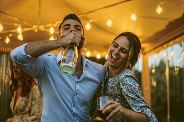 Foto coppia di giovani amici che si divertono a bere a una festa - persone ubriache che ballano insieme